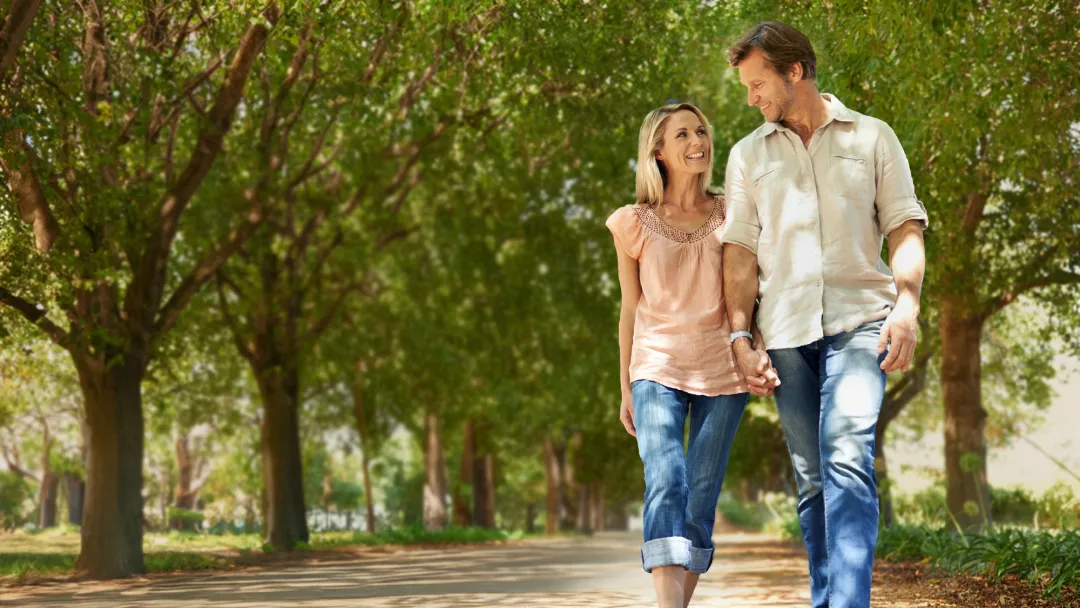 Adult couple walking in park lined by trees