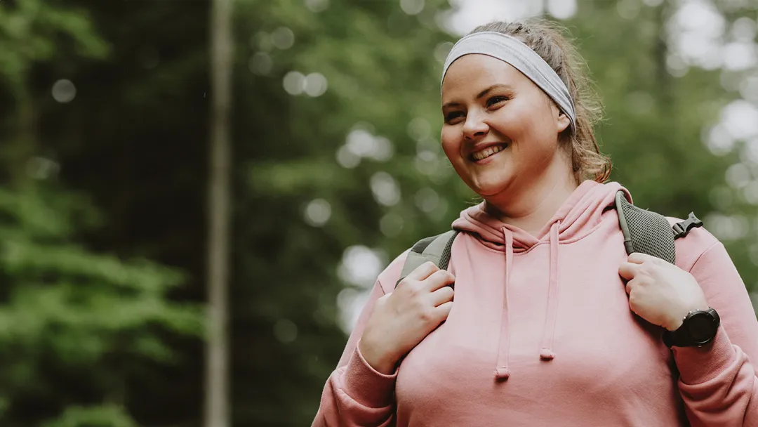 Woman smiling while she is on a hike outdoors.