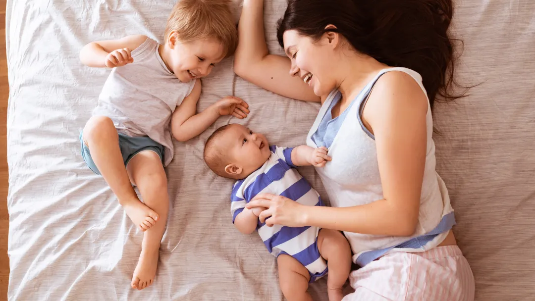 A mom snuggles her two children in bed.