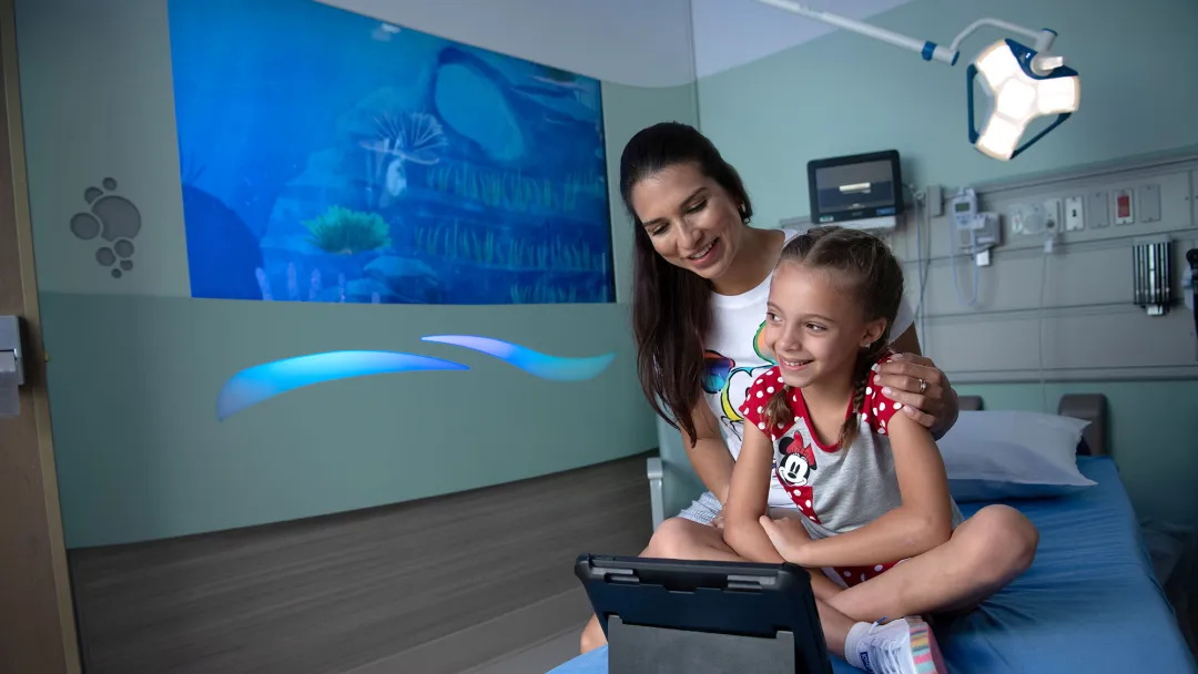 A mother and her daughter viewing a tablet device in a hospital room