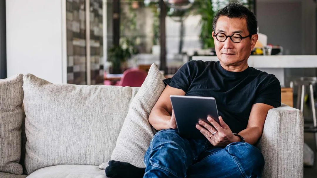An asian man reading in his living room