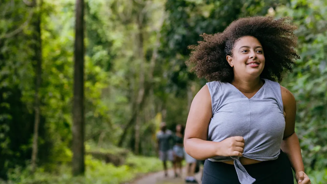 Hispanic woman running outdoors in a forest.