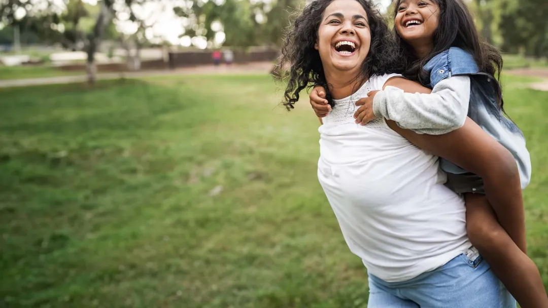 Mother with daughter on back outside