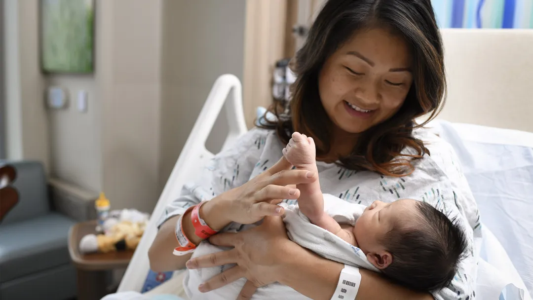Mother holding her newborn baby in a hospital bed