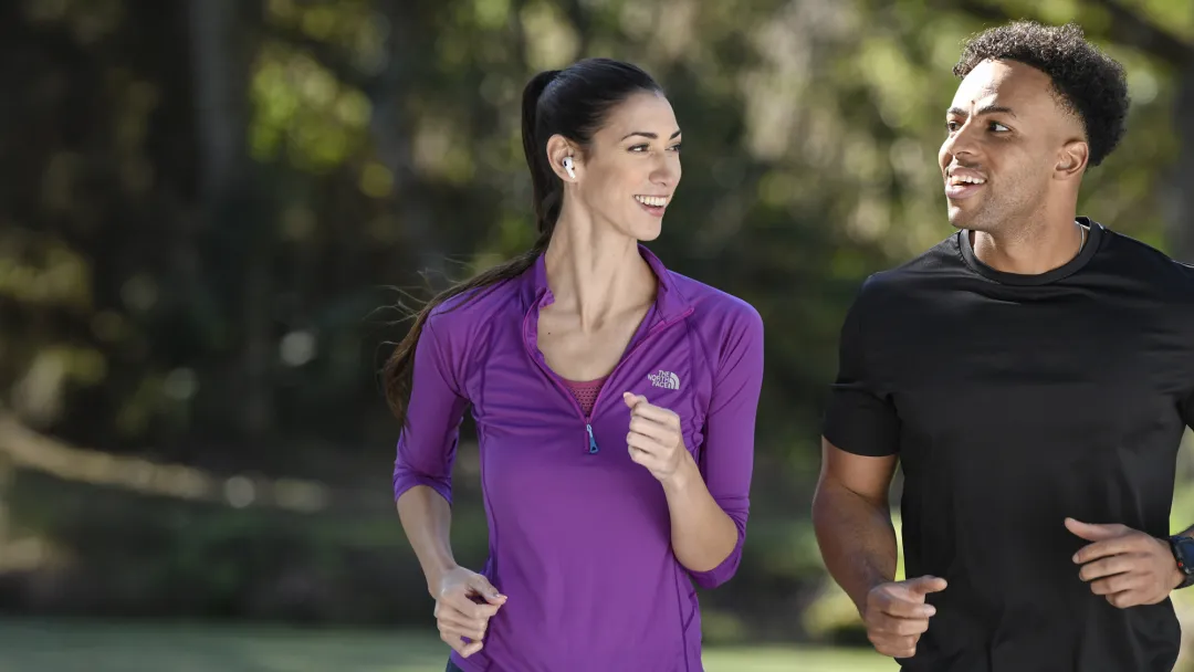 A Couple Runs Together in the Park While Sharing a Laugh
