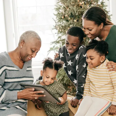 Family looking at photo album next to a Christmas tree
