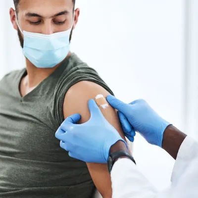 Medical professional putting a bandaid on a man after he received a covid-19 vaccine booster shot