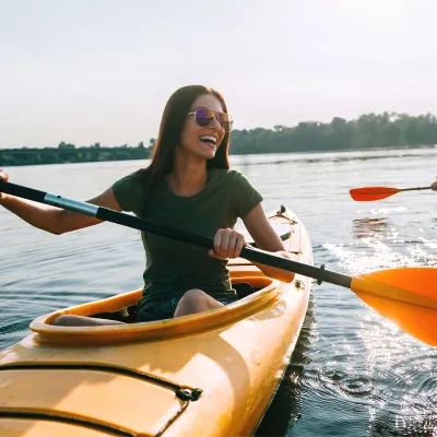 A Woman Kayaks With a Friend on a Lake 
