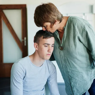 A Mother Comforts Her Son By Kissing Him on the Top of His Head.