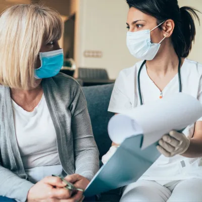 A Health Care Professional Goes Over Paperwork with a Patient in the Waiting Room.