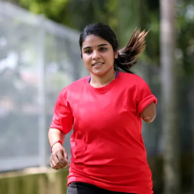 A Teenage Girl with One Lower Arm Runs in a Park.