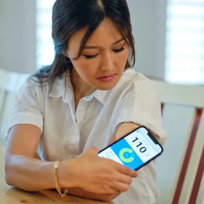 A Woman Checks Her Blood Sugar Levels at Her Kitchen Table.