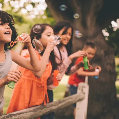 A group happy children blowing bubbles during the summer.