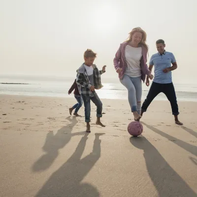 A family plays a friendly game of soccer on the beach