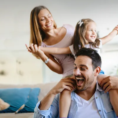 Man laughing carrying his daughter on his shoulders