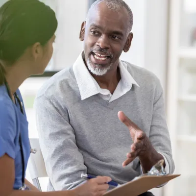 A man asks questions at his appointment with his doctor.