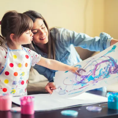 A mother and young daughter painting together. 