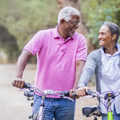 Older couple walking with bikes.