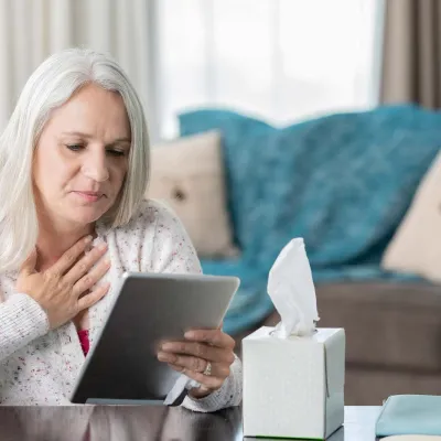 Woman holding heart, looking at tablet