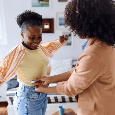 A woman measuring her daughter's waist.