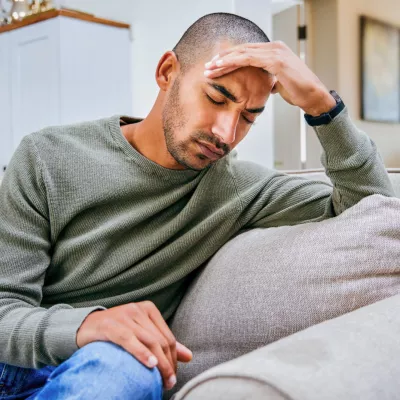 A young man holds his hand against his forehead.