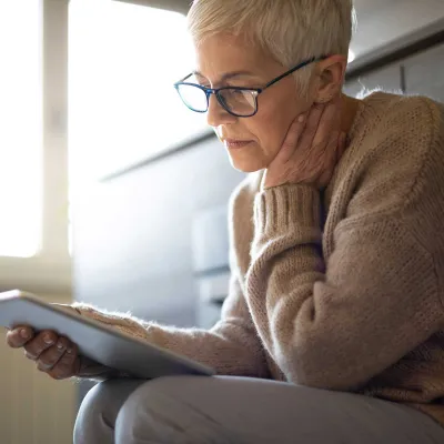 A senior seriously reading while on her tablet.