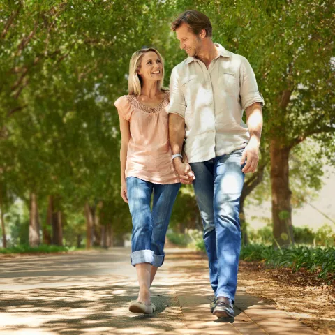 Adult couple walking in park lined by trees