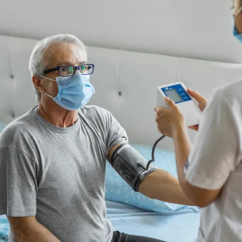 A home care nurse takes a patient's blood pressure.