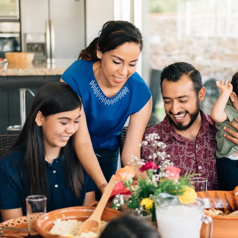 A Hispanic Family Sits Down to a Meal in Their Home.
