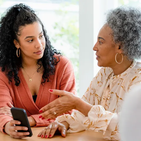 Mother and Daughter Have a Discussion in the Kitchen While Holding a Cell Phone