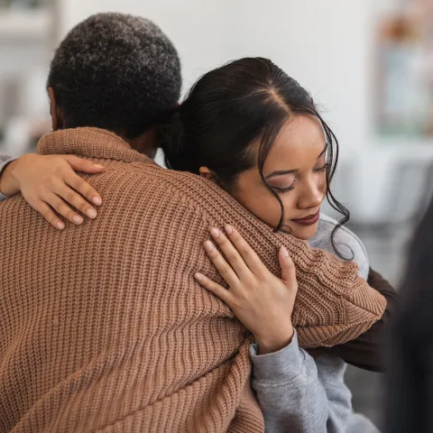 Two People Embrace While Sitting on a Couch.