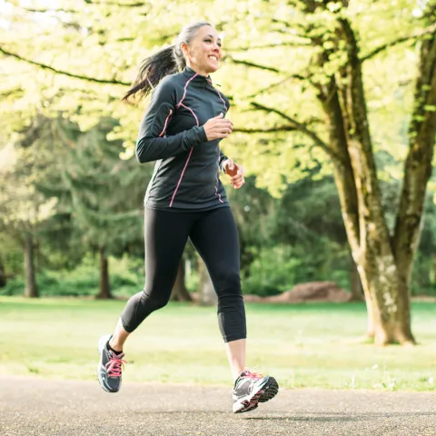 A Woman Runs Through a Wooded Park