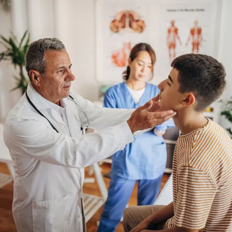 A Doctor Examines a Teenage Patients Face While a Nurse Takes Notes