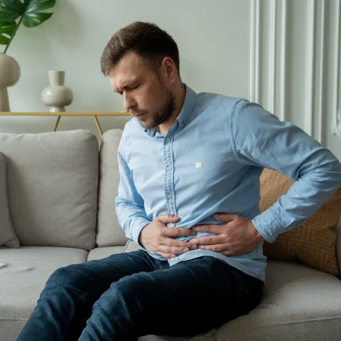A Man Winces in Pain as He Hold's his Side