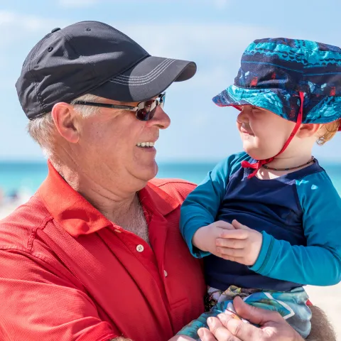 A Grandfather Holds His Grandson on the Beach