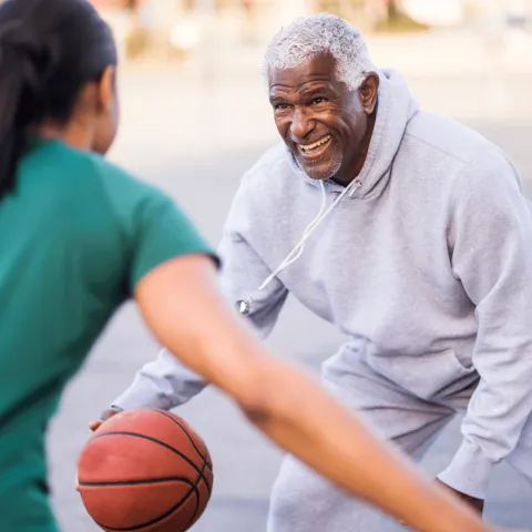 A Senior Man Plays Basketball with an Adult Child