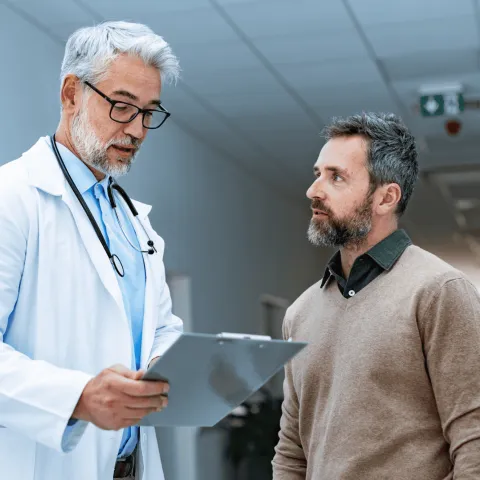 A Doctor Speaks to a Patient in the Hallway of a Practice.