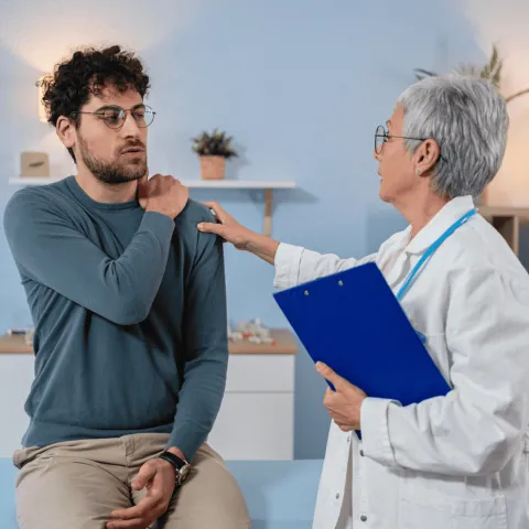 Man with Doctor holding his shoulder.