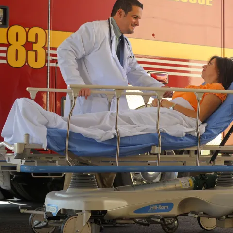 Woman arriving in a stretcher from ambulance with a doctor by her side.