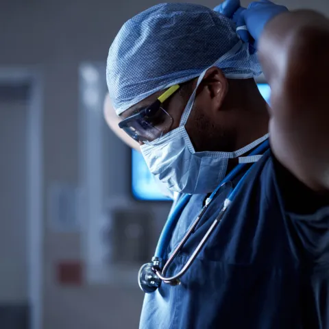 A surgeon puts on a mask.
