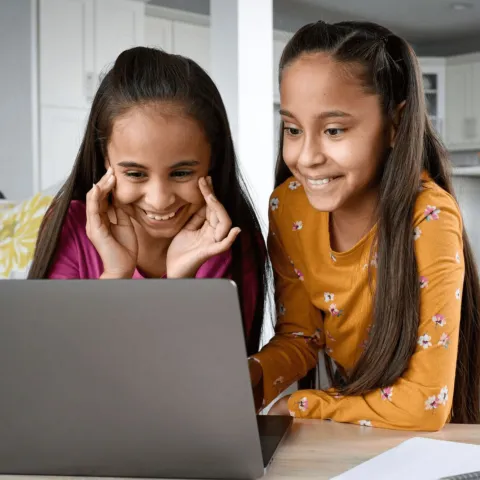 A mother and daughter doing schoolwork on a laptop.