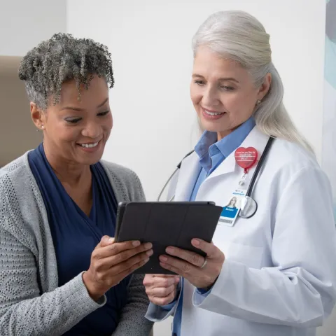 A woman and her female doctor look at information on a tablet.