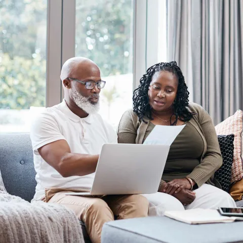 Man and woman reviewing paperwork with computer on lap