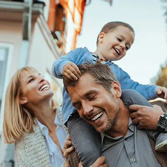 Smiling Parents with Son on Father's shoulders outdoors
