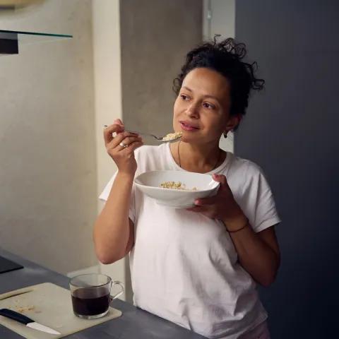 A hispanic woman eating a bowl of food.