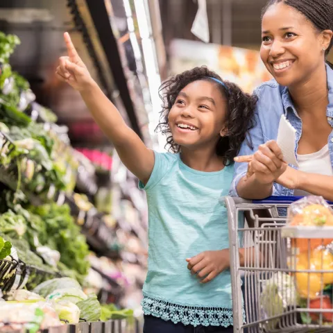 A mother and daughter shop for nutrient-rich vegetables at the supermarket. 