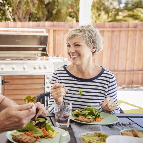 A couple eats a healthy meal together outside.