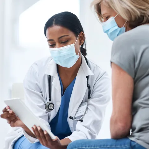 A physician showing something to her patient on her business tablet