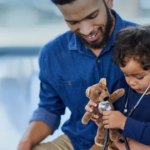 Father and son playing with teddy bear