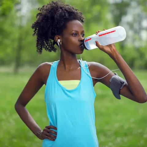 A woman taking a water break during her run.